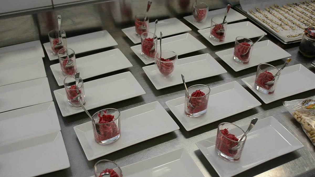 Rote Mousse in kleinen Gläsern auf weißen Tellern, angerichtet in der Küche