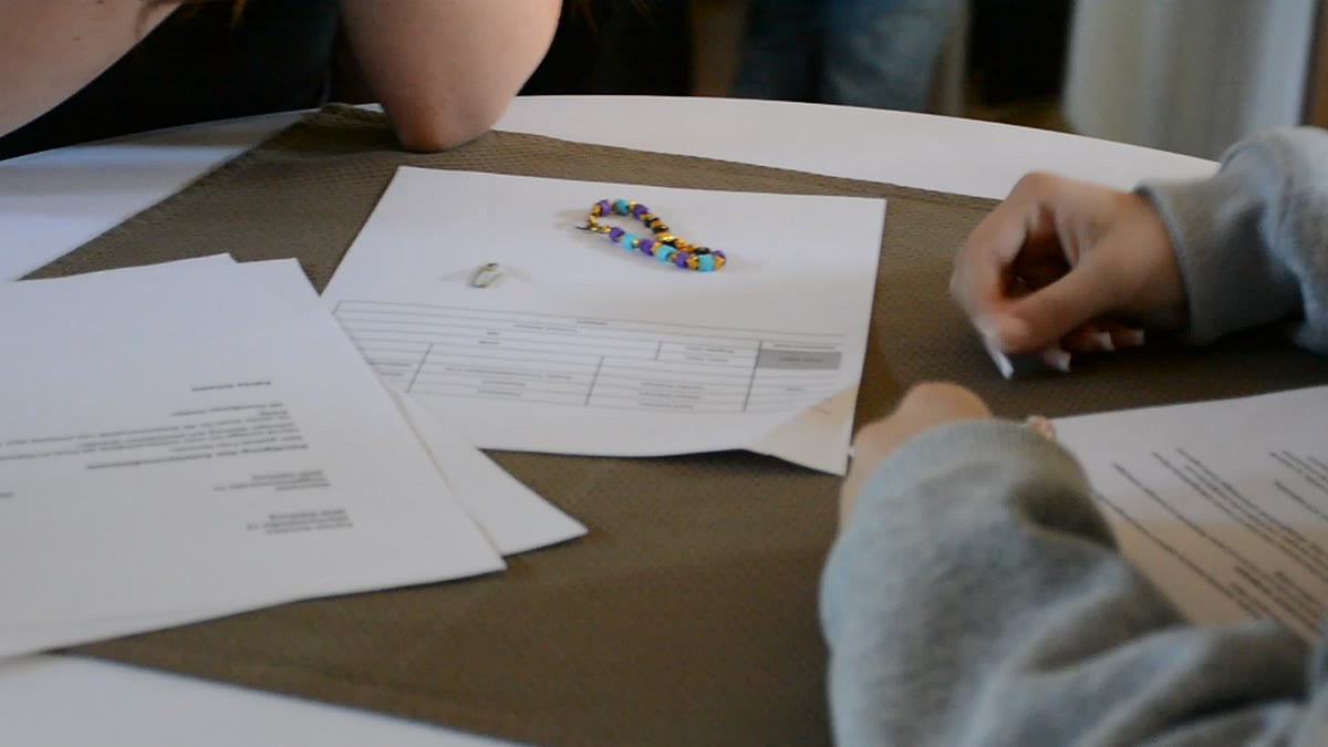 Akten, ein Perlenarmband und ein Ring als Beweismittel auf dem Tisch