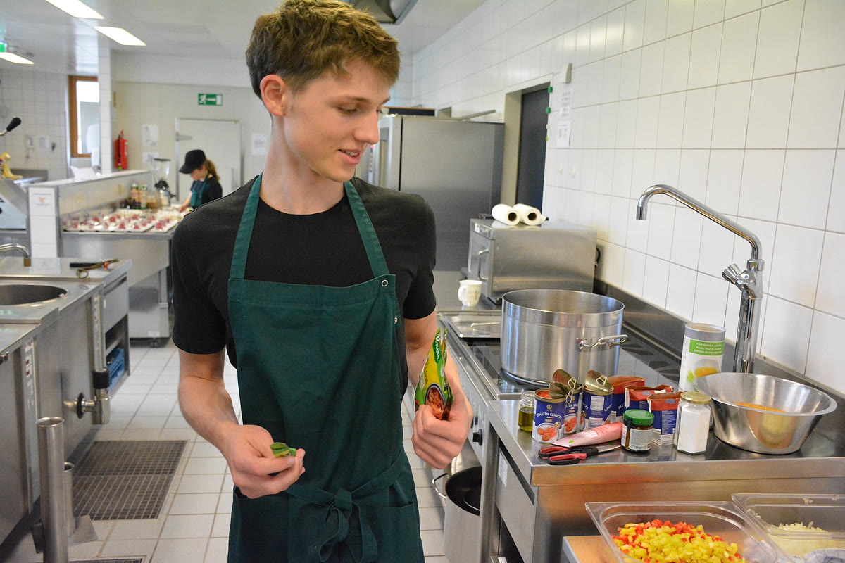 In der Schulküche: ein Schüler bereitet die Speisen vor
